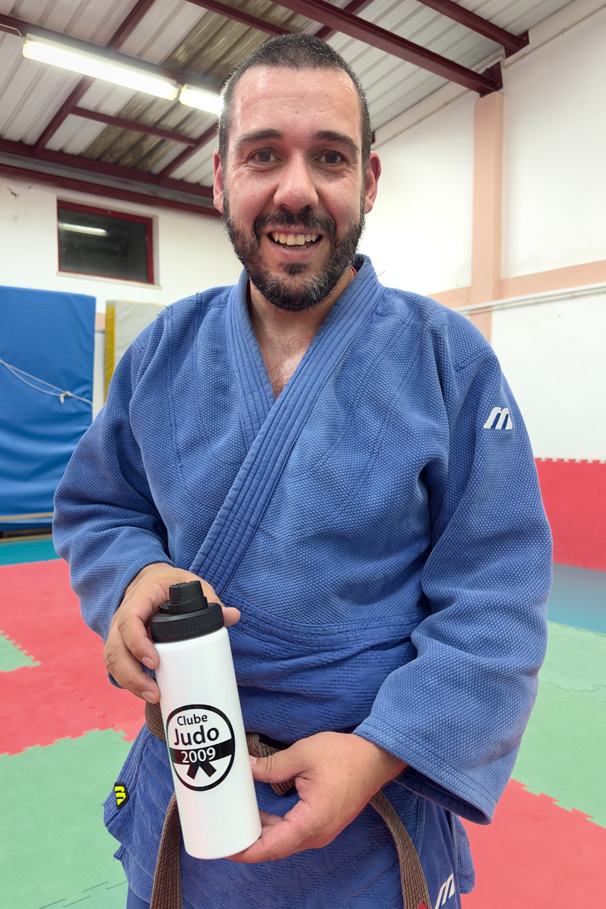 Judoca de judogi azul a apresentar uma das novas garrafas com o emblema do Clube de Judo 2009